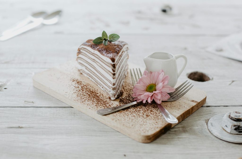 delicious piece of cake and flower on wooden table